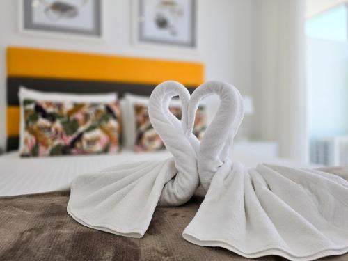 dos cisnes con forma de corazones sentados en una cama en Apartment Praia Rocha Residence Jade, en Portimão