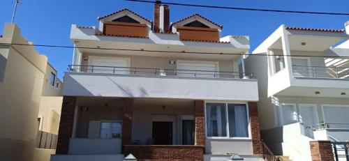 a white house with a balcony on top of it at ANEMOS SURF VIEw in Artemida