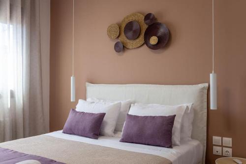 een slaapkamer met een bed met kussens en hoeden aan de muur bij Koukounaraki Apartment 1 in Skiathos-stad