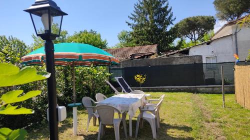 a table with chairs and an umbrella in a yard at Casa Perla vicino al mare in Massa