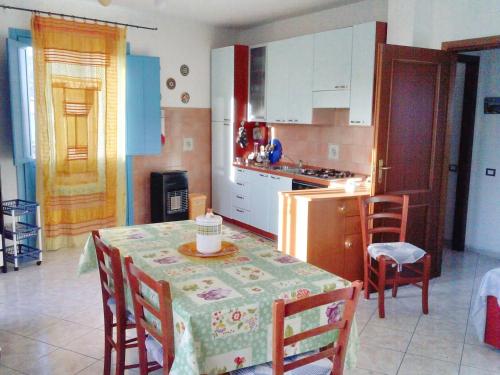 a kitchen with a table and chairs and a kitchen with white cabinets at 2 bedrooms apartement at Lotzorai 800 m away from the beach with furnished balcony in Lotzorai