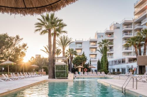 una piscina frente a un hotel con palmeras en Apartamentos Vistasol en Magaluf