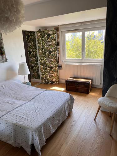 une chambre avec un lit, une fenêtre et une chaise dans l'établissement Appartement de charme vue sur Loire, à Nantes