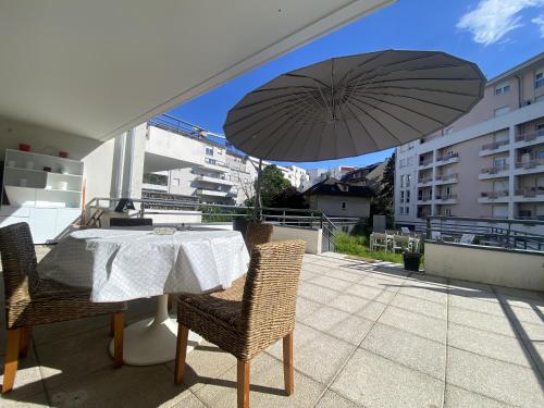 a table and chairs with an umbrella on a balcony at Au Clos Celestin in Annemasse