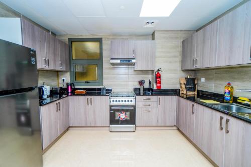 cocina con armarios de madera y horno con fogones en 1 BR Apt, Miracle Garden with RoofTop Pool, King Bed, Gym,100mbps, en Dubái