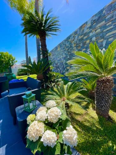 a garden with palm trees and flowers on a patio at Dimora dei lidi in Fontane Bianche