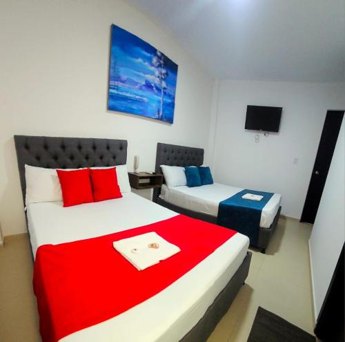 a bedroom with two beds with red and blue pillows at ANAJIRAWAA HOTEL in Ríohacha