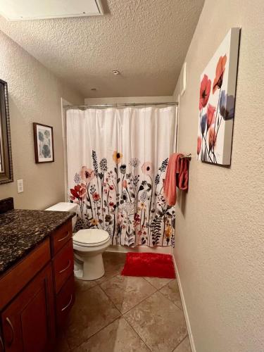a bathroom with a toilet and a shower curtain with flowers at Gated Condo Heated Pool Spa Gym Near Zoo in Phoenix