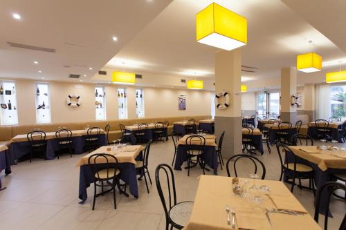 una sala da pranzo con tavoli, sedie e luci gialle di Hotel Costazzurra Museum & Spa a San Leone