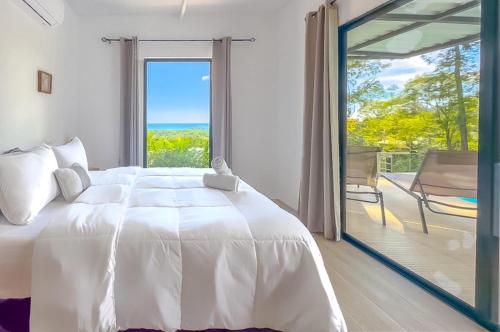 1 dormitorio con 1 cama blanca grande y puerta corredera de cristal en Modern Home with Panoramic Ocean View and Pool, en Ojochal