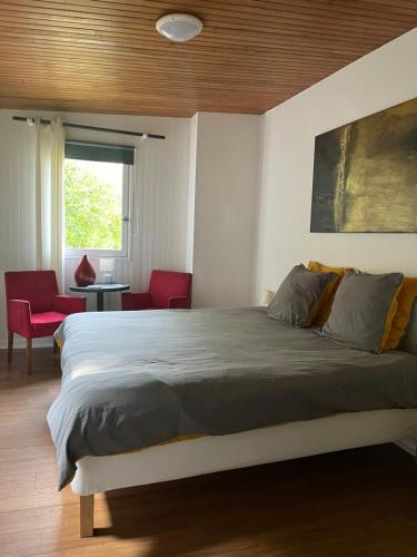 um quarto com uma cama grande e cadeiras vermelhas em Merlin les pieds dans l'eau em Saint-Aignan