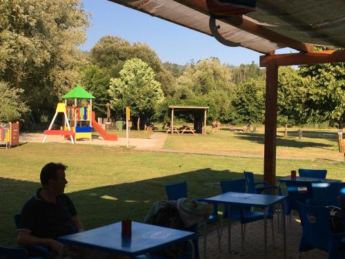 a man sitting at tables in a park with a playground at Casa Pintarolas in Lousã