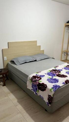 um quarto com uma cama com um cobertor floral em Espaço Zen em Cascavel