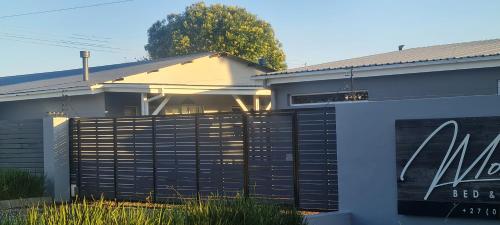 a house with a black fence in front of it at Mosswood Bed & Breakfast in Graskop