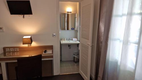 a hotel room with a desk and a table and a window at Hotel Restaurant du Centre et du Lauragais in Castelnaudary