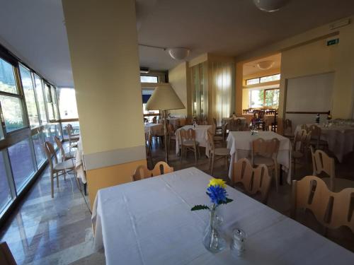 ein Restaurant mit Tischen und Stühlen und eine Vase mit Blumen darauf in der Unterkunft Hotel Prestige 3 Stars in Rimini