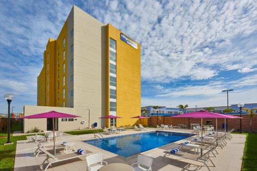 a hotel with a pool and chairs and a building at City Express by Marriott Rosarito in Rosarito