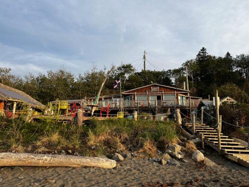 a house on a beach with stairs and a house at Auberge Festive Sea Shack in Sainte-Anne-des-Monts