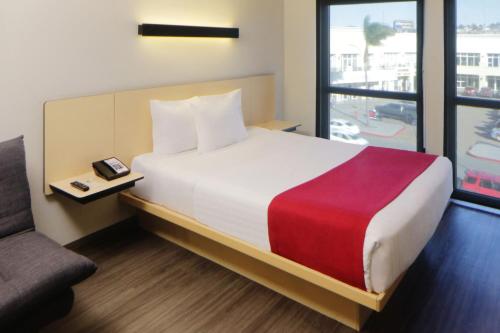 a bedroom with a bed and a couch and a window at City Express by Marriott Rosarito in Rosarito