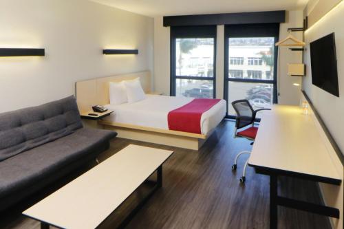 a hotel room with a bed and a couch at City Express by Marriott Rosarito in Rosarito
