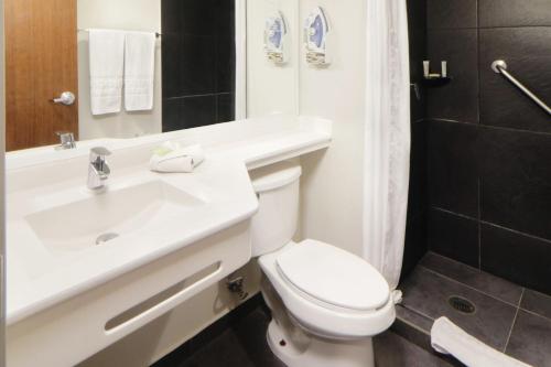 a bathroom with a white toilet and a sink at City Express by Marriott Rosarito in Rosarito