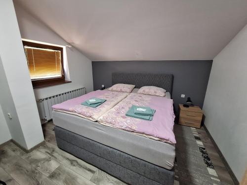 a small bedroom with a bed with pink sheets at Apartman Dujmović 1 in Otočac