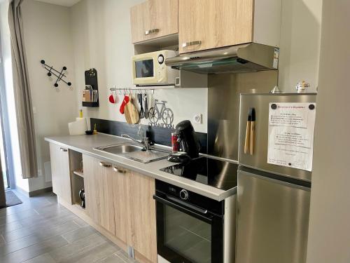a kitchen with a stainless steel refrigerator and a sink at « La Bicyclette » 35m2 tout équipé centre ville in Mayenne
