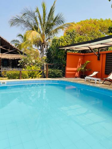 einen Pool mit zwei Stühlen und ein Haus in der Unterkunft Chris Espace in Toliara