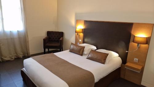 a hotel room with a large bed and a chair at Hotel Restaurant du Centre et du Lauragais in Castelnaudary