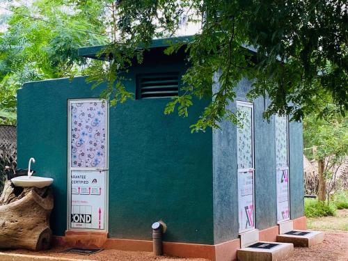 a green building with a sink next to a tree at Yala Village Eco Tree House in Tissamaharama