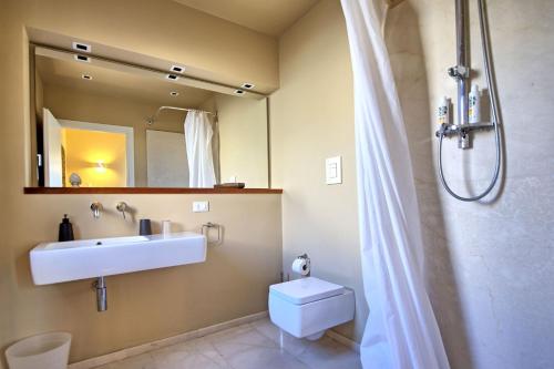 Un baño con lavabo, inodoro y espejo. en Villa Casale by PosarelliVillas, en Bisciano