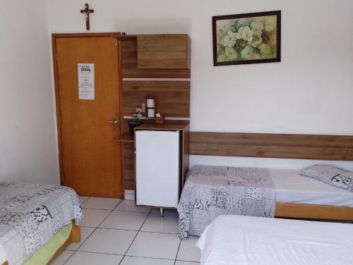 een kamer met 2 bedden en een deur met een spiegel bij Hotel Portal dos anjos in Aparecida
