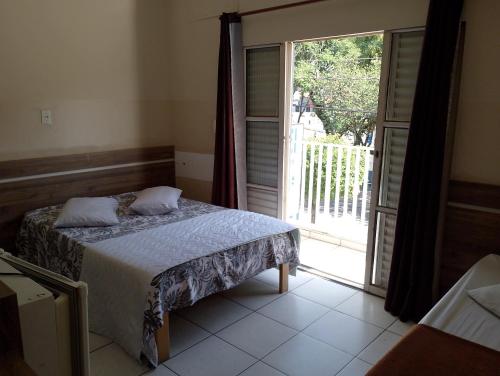 阿帕雷西達的住宿－Hotel Portal dos anjos，一间卧室设有一张床和一个滑动玻璃门