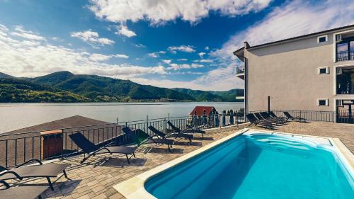 a swimming pool with chairs and a building and water at Pensiunea Rodan in Orşova