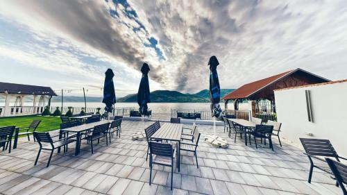 a deck with tables and chairs and umbrellas at Pensiunea Rodan in Orşova