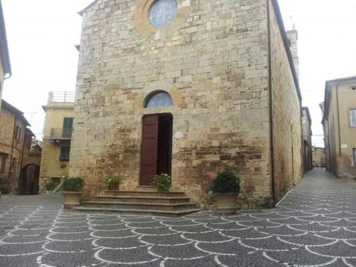 a small brick building with a red door on a street at Casa Ines - Borgo di Bibbona in Bibbona