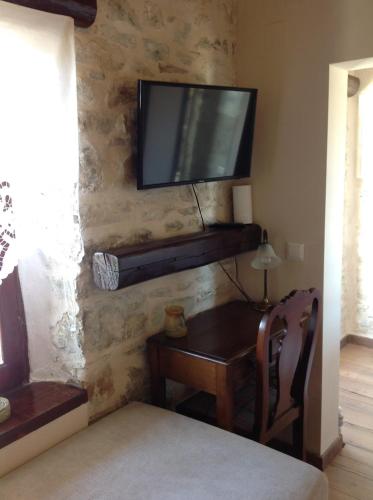 a living room with a tv on a stone wall at Μακρινίτσα Αλώνια in Makrinítsa