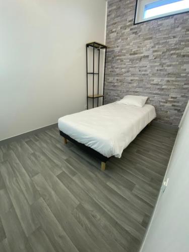 1 dormitorio con cama y pared de ladrillo en APPARTEL 76 CHAMBRES, en Rouxmesnil-Bouteilles