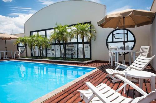 una piscina con sedie, tavolo e ombrellone di The Palace Flat Moema a San Paolo
