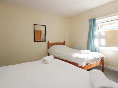 two beds in a room with a window at Newfield Apartment 2 in Broughton in Furness