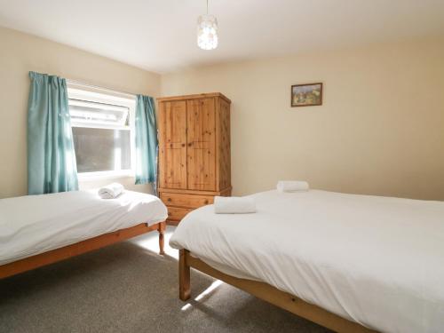two twin beds in a room with a window at Newfield Apartment 2 in Broughton in Furness