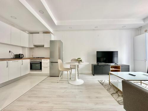 een witte keuken met een tafel en stoelen. bij Double Studio B106 StayInn by Cosmopolis in Ştefăneştii de Jos