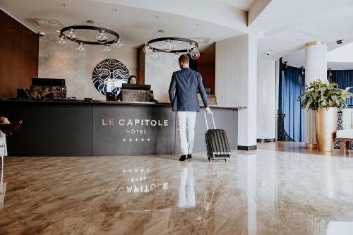 a man with a suitcase in a hotel lobby at Le Capitole Hotel in Quebec City