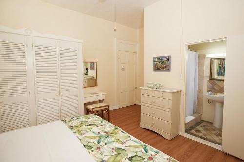 Southern Surf Beach Apartments في بريدج تاون: غرفة نوم بسرير ومغسلة ومرآة