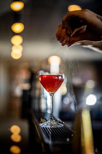 a person preparing a drink in a martini glass at Le Capitole Hotel in Quebec City