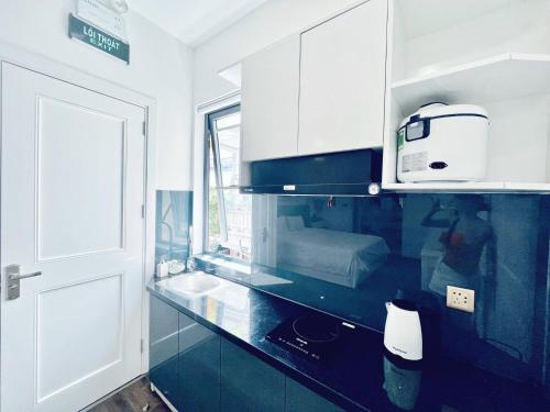 a kitchen with white cabinets and a sink and a microwave at Amy Hotel & Apart' Hue in Hue