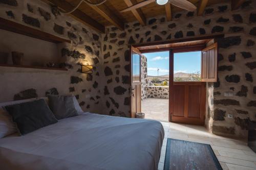 1 dormitorio con 1 cama y puerta corredera de cristal en Hotel Rural El Cabo de "Casa Marcos", en Villaverde