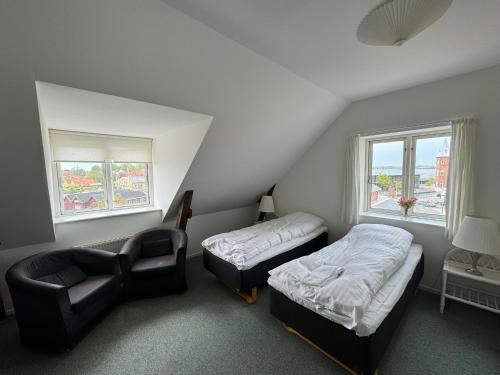 a room with two beds and a couch and a chair at Hotel Postgaarden in Skælskør