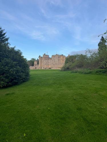 a large grass field with a castle in the background at East Lodge - Chillingham Castle in Alnwick