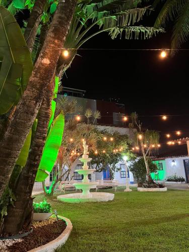 a park at night with a fountain and palm trees at Pousada Puerta Del Sol Rio das Ostras in Rio das Ostras